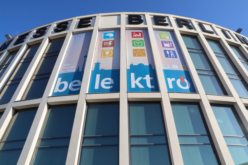Foto von der Eingang Süd Fassade mit belektro Banner und der Abbildung aller Rahmenprogramm Icons